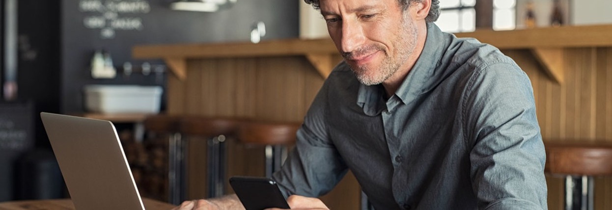 Couple sitting on couch looking at laptop smiling